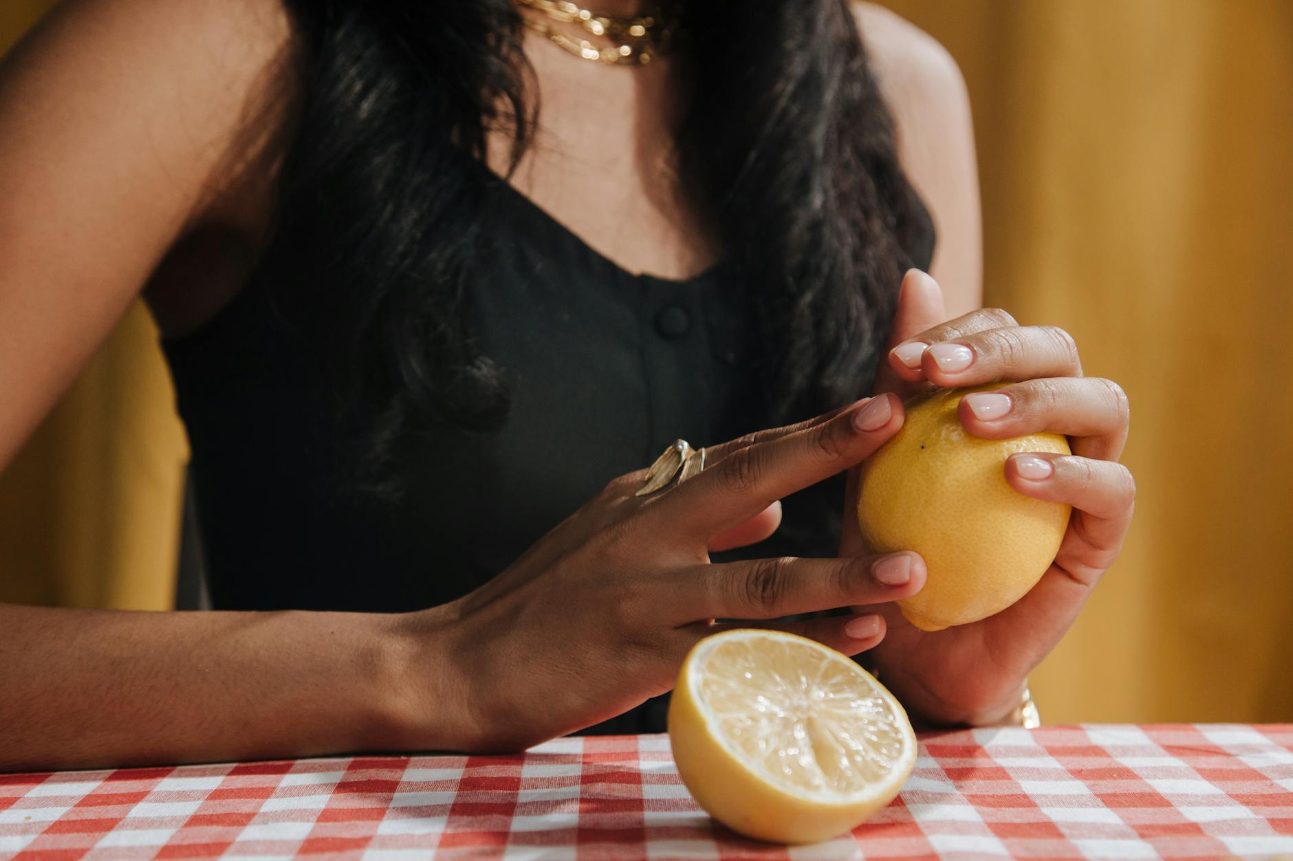 A close-up of hands holding a fresh lemon at a dining table, symbolizing renewal and fresh sensation