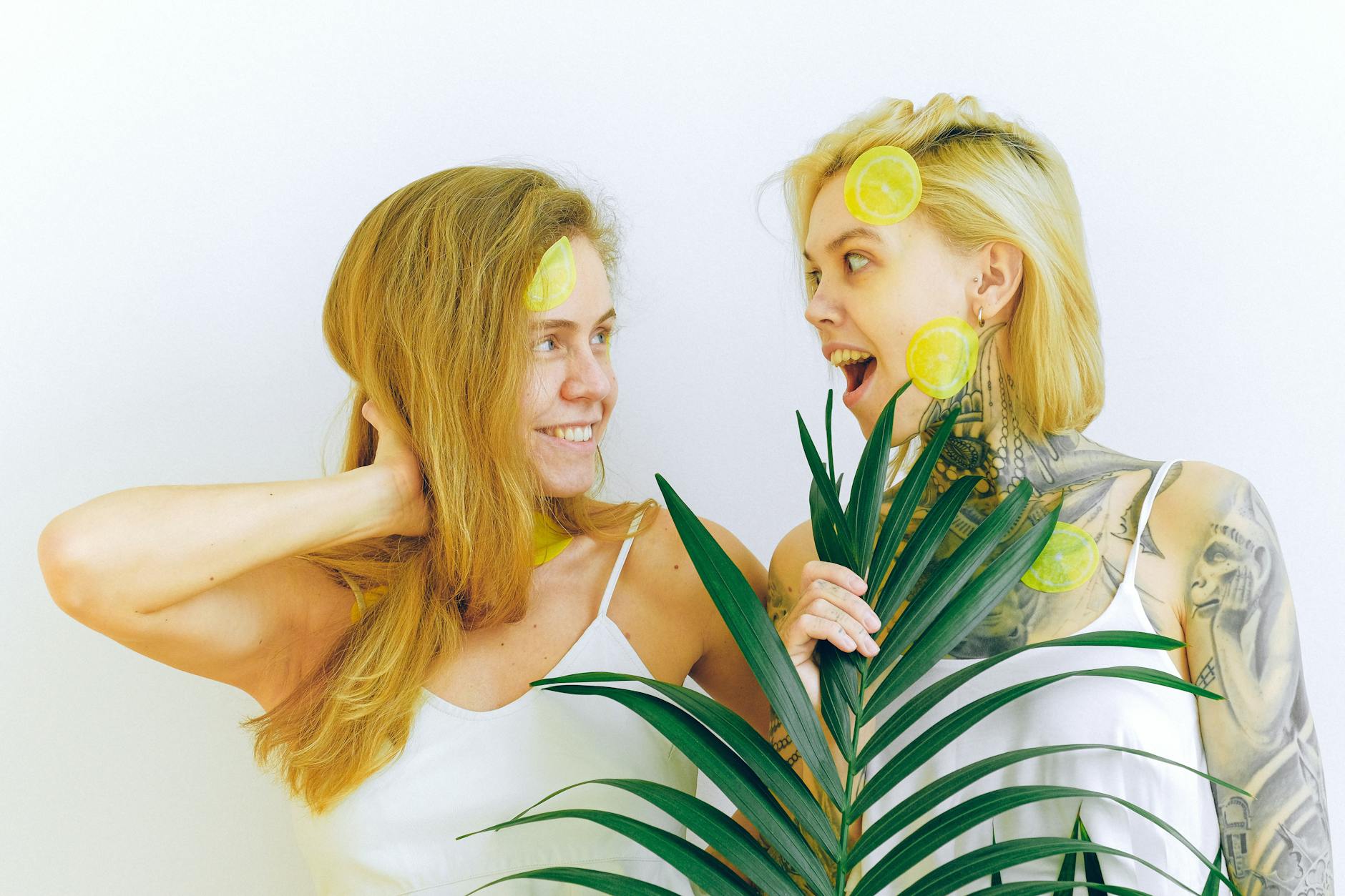 Two women smiling together with lemon slices, expressing joy and comfort in a bright indoor setting