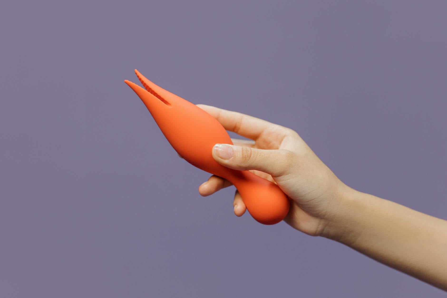 Hand holding a lemon vibrator against a minimalistic purple backdrop, showcasing modern sensuality and wellness.